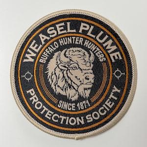 May include: Circular patch with the text "WEASEL PLUME PROTECTION SOCIETY" and "BUFFALO HUNTER HUNTERS" around a central image of a bison head. The patch is black, tan, and orange with the text "SINCE 1871".