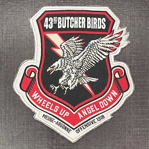 Op de afbeelding: Geborduurde patch met een zwart schildontwerp, een witte adelaar en een bliksemschicht. De patch leest "43rd BUTCHER BIRDS" en "WHEELS UP ANGEL DOWN" met "MEUSE-ARGONNE OFFENSIVE 1918" in rood en wit.