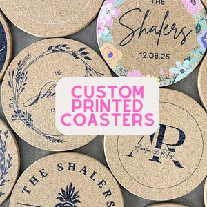 May include: A collection of custom printed coasters with various designs. Some coasters feature initials, names, and dates, while others display floral patterns and a pineapple. The coasters are made of a light brown material.