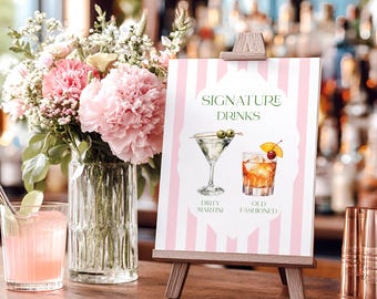 Puede incluir: Un letrero rectangular sobre un caballete de madera con rayas verticales rosas y blancas. El texto dice SIGNATURE DRINKS, DIRTY MARTINI y OLD FASHIONED, acompañado de ilustraciones en acuarela de una copa de martini y un vaso de cóctel.