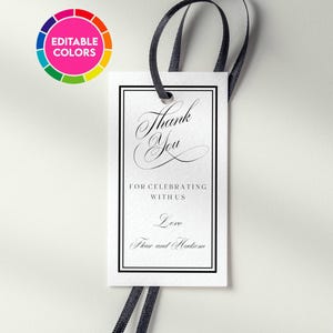 Może przedstawiać: Prostokątna biała papierowa zawieszka z czarną podwójną ramką i czarną wstążką. Tekst brzmi: Thank You FOR CELEBRATING WITH US Love Fleur and Hudson. Okrągła ikona w lewym górnym rogu przedstawia koło kolorów z napisem EDITABLE COLORS.