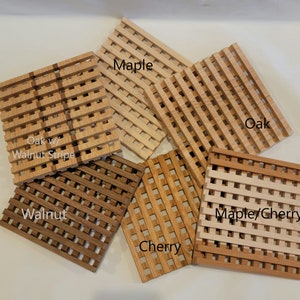 May include: Six square wooden coasters in different wood types: oak with walnut stripe, walnut, cherry, maple, oak, and maple/cherry.