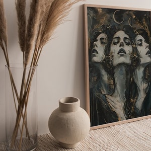 May include: A framed print of a digital painting featuring three women's faces with a dark blue and gold background. The women's faces are partially obscured by their long dark hair. The background features a gold crescent moon and stars.