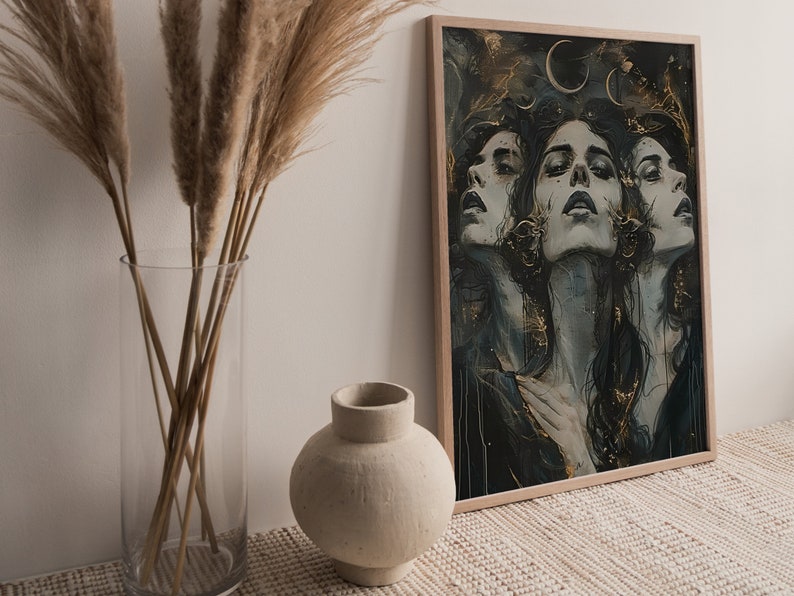 May include: A framed print of a digital painting featuring three women's faces with a dark blue and gold background. The women's faces are partially obscured by their long dark hair. The background features a gold crescent moon and stars.