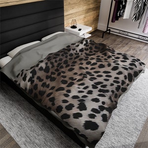 May include: A brown and black leopard print duvet cover with a gray and white patterned bedspread on a black headboard bed.