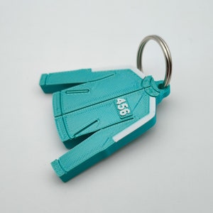 Peut inclure: Porte-clés imprimé en 3D de couleur bleu sarcelle en forme de veste avec une bande blanche et le numéro 456 imprimé dessus.