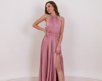 Könnte beinhalten: Ein bodenlanges Kleid aus altrosa Satin mit hohem Neckholder-Ausschnitt, gerafftem Oberteil, betonter Taille und einem langen Rock mit hohem Seitenschlitz. Der Stoff hat eine glatte, reflektierende Oberfläche und fällt bis zum Boden.