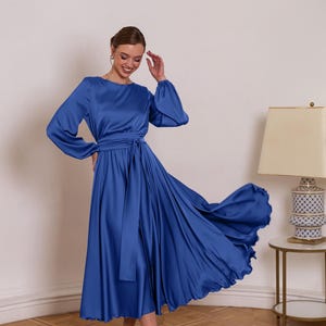 a woman in a blue dress standing in a room