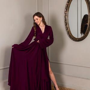 a woman in a long dress standing in front of a mirror