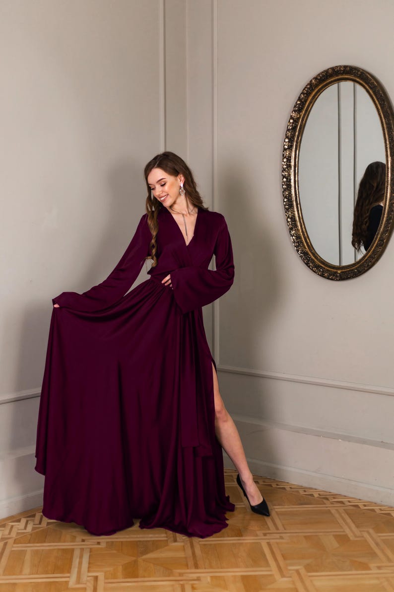 a woman in a long dress standing in front of a mirror