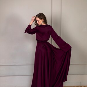 a woman in a long purple dress standing on a wooden floor