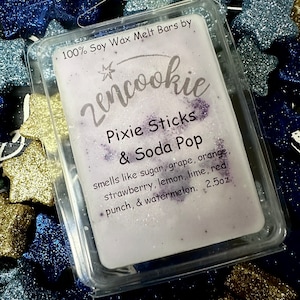 May include: A clear plastic container holding a white wax melt bar with purple specks. The label reads "zencookie Pixie Sticks & Soda Pop" and lists scents like strawberry and watermelon. The bar weighs 2.5oz. The background is filled with glittery blue and gold star shapes.