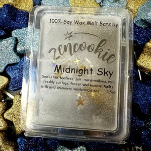 May include: A clear plastic container with a white wax melt bar inside. The wax melt is labeled "Midnight Sky" and is described as smelling like bonfires, salt, marshmallows, rain, freshly cut logs, forest, and incense. The wax melt is 100% soy wax and is 2.5 ounces.