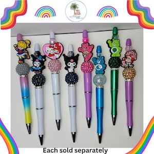 May include: Eight colorful pens with different cartoon character toppers. Each pen has a white barrel and a clear, glittery ball charm. The toppers include Care Bears, Hello Kitty, My Melody, and Little Twin Stars. The text "Each sold separately" is at the bottom of the image.