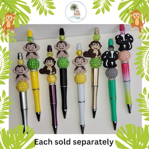 May include: A collection of decorative pens with monkey and skunk toppers. The pens have various colors, including yellow, black, white, and green. The text "Each sold separately" is at the bottom of the image.