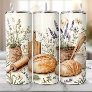May include: Three stainless steel tumblers with a white background and a floral design. The design features lavender, wildflowers, bread, a rolling pin, and a wooden cutting board.