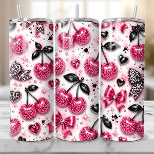 May include: Three stainless steel tumblers with a cherry design. The design features pink glitter cherries, black leaves, leopard print bows, pink bows, and heart-shaped gems on a white background. Each tumbler has a straw.