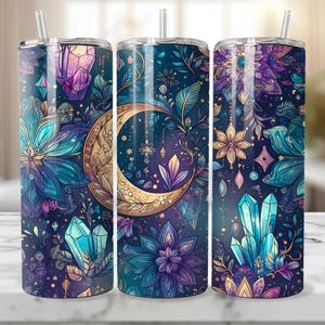 May include: A set of three stainless steel tumblers with a celestial design. The tumblers feature a dark blue background with a crescent moon, crystals, and floral elements in shades of purple, teal, and gold. Each tumbler has a straw and a lid.