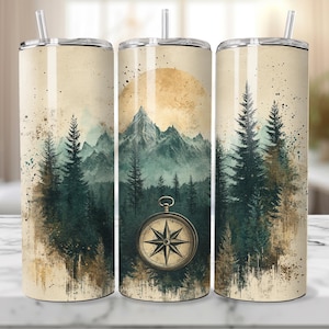 May include: Three stainless steel tumblers with a vintage-inspired design featuring a mountain range, pine trees, and a compass. The tumblers have a cream-colored background with a subtle watercolor effect.