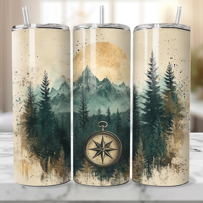 May include: Three stainless steel tumblers with a vintage-inspired design featuring a mountain range, pine trees, and a compass. The tumblers have a cream-colored background with a subtle watercolor effect.