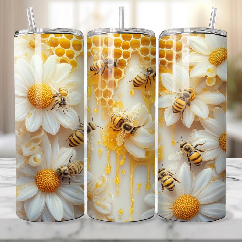 Puede incluir: Tres vasos de acero inoxidable con un dise&ntilde;o de margarita blanca y panal de abejas. Los vasos presentan un dise&ntilde;o de miel que gotea y abejas con rayas amarillas y negras.