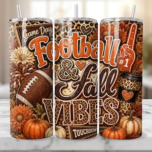 May include: A cylindrical tumbler with a straw featuring a fall-themed design with leopard print, footballs, pumpkins, and orange flowers. The text reads Game Day, Football & Fall Vibes, and Touchdown, with a number one foam finger graphic.