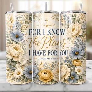 May include: A stainless steel tumbler with a floral design in cream, blue, and gold. The tumbler features the text "FOR I KNOW The Plans I HAVE FOR YOU" and a cross. The design includes flowers, leaves, and a dove.