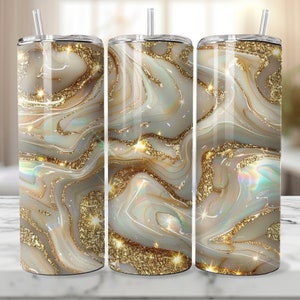 May include: Three stainless steel tumblers with a gold and white marble design. The tumblers have a shiny, glittery finish.