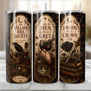 May include: Three black and gold stainless steel tumblers with straws. Each tumbler features gothic-style illustrations and text: "The Villain Era Society," "I Like My Men Morally Grey," and "Daggers Out, Crown On."