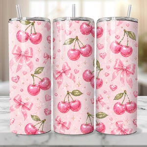 May include: Three pink tumblers with a cherry and bow pattern. The design features watercolor-style cherries, bows, hearts, and stars on a light pink background. Each tumbler has a silver lid and a clear straw.