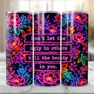 May include: A cylindrical tumbler with a straw featuring a black background covered in neon-colored floral patterns in pink, purple, blue, and orange. The text "Don't let the ugly in others kill the beauty in you." is printed in a neon pink font.