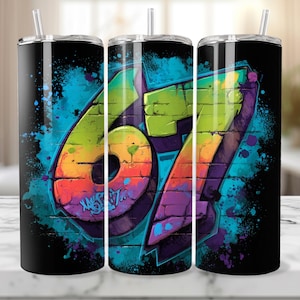 Könnte beinhalten: Drei schwarze Edelstahlbecher mit einem farbenfrohen Graffiti-Design. Das Design zeigt die Zahl "67" in einer lebendigen, mehrfarbigen Schriftart im Ziegelstil mit blauen und grünen Farbspritzern. Die Becher haben einen Strohhalm.