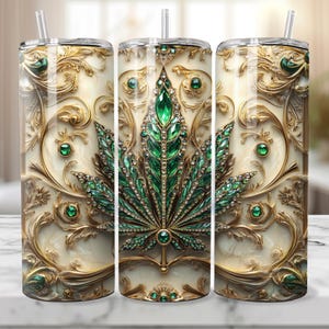 May include: A stainless steel tumbler with a gold and green design. The design features a marijuana leaf with emerald green gemstones and gold accents. The tumbler is perfect for holding hot or cold beverages.