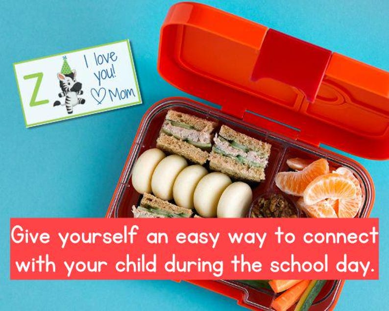 Puede incluir: Una lonchera roja y naranja abierta, llena de s&aacute;ndwiches, gajos de mandarina y verduras. Una tarjeta con una ilustraci&oacute;n de cebra y el texto "I love you! Mom" est&aacute; al lado de la lonchera. El texto "Give yourself an easy way to connect with your child during the school day" est&aacute; en la parte inferior.