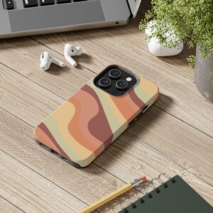 May include: A smartphone case featuring a wavy, multi-colored pattern in shades of terracotta, muted orange, cream, and sage green. The case has a cutout for a triple-lens camera system and covers the back and sides of the mobile device.
