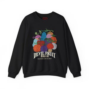 May include: Black sweatshirt featuring a colorful graphic of various fruits with the text "DEVIL FRUIT" and Japanese characters. Below the text is "Incarnation of the Sea Devil". The fruits are in shades of red, blue, purple, and orange.