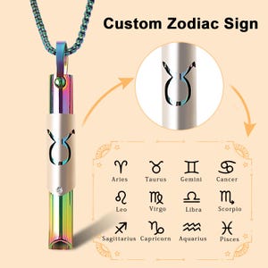 May include: A silver necklace with a pendant shaped like a Taurus zodiac sign. The pendant is a hollow cylinder with a rainbow iridescent finish. The pendant is surrounded by a silver chain. The image also shows a chart of all the zodiac signs.