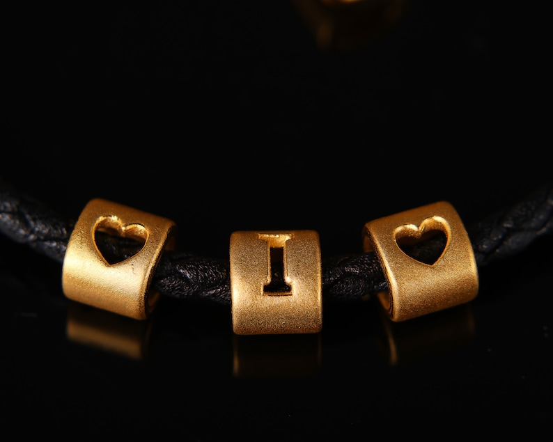 May include: A black leather bracelet with gold beads that spell out "I love you".