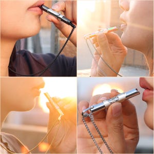 May include: Four different silver whistles on chains. Each whistle has a different design and is being blown by a person. The whistles are on a silver chain.