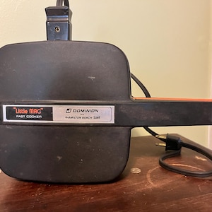 May include: Black electric "Little Mac" fast cooker with a black handle and a silver label that reads "Dominion by Hamilton Beach Scovill".