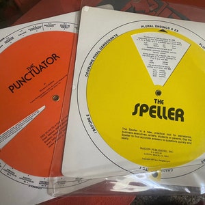 May include: Two yellow and orange circular educational tools, "The Punctuator" and "The Speller", with rotating dials to help with grammar and spelling. The Speller includes instructions for use and copyright information.