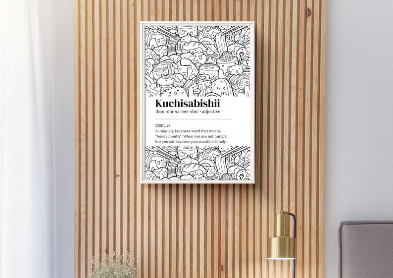May include: A framed monochrome print featuring the word "Kuchisabishii" and its phonetic spelling. The print has a doodle-style illustration of food and characters. The definition of the Japanese word is also included.
