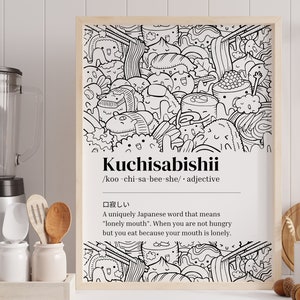 May include: A framed monochrome print displaying the Japanese word "Kuchisabishii" and its definition. The illustration depicts a playful assortment of food items, including sushi and ramen, with cartoon-style faces.
