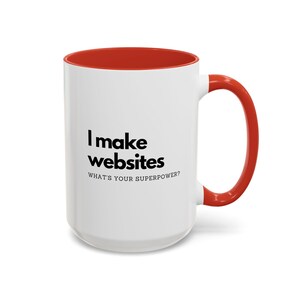 Puede incluir: Taza de café de cerámica blanca con borde y asa rojos. La taza tiene texto negro que dice "Hago sitios web. ¿Cuál es tu superpoder?"