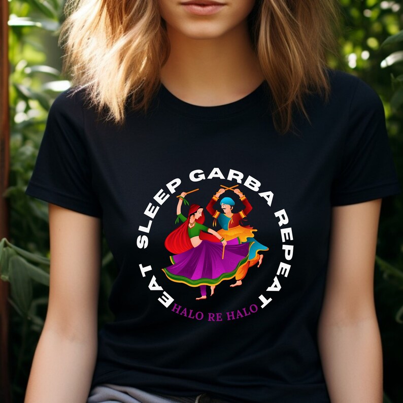 Puede incluir: Camiseta negra con un gr&aacute;fico circular blanco que muestra a dos personas bailando con ropa colorida. El texto alrededor del c&iacute;rculo dice "Eat Sleep Garba Repeat" y "Halo Re Halo".