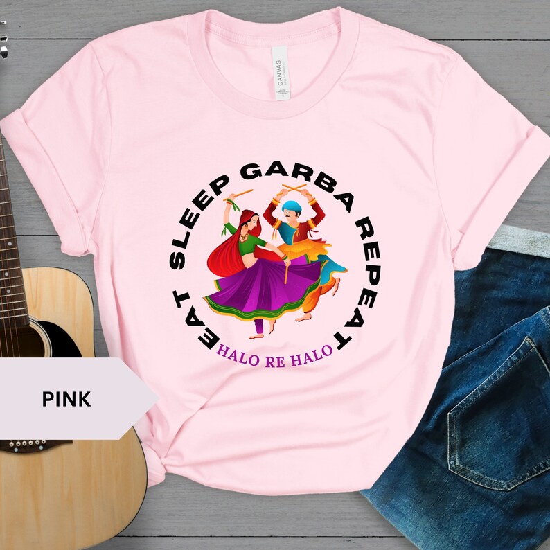 Puede incluir: Camiseta rosa con un gr&aacute;fico circular negro que representa a dos personas bailando con el texto "Eat Sleep Garba Repeat Halo Re Halo".