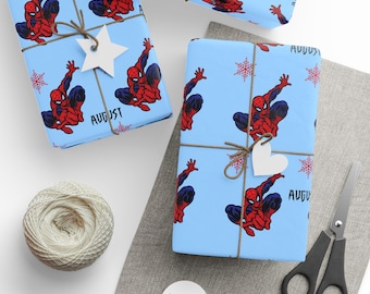 May include: Gift wrapping paper featuring a repeating pattern of the Spider-Man character in red and blue on a light blue background. The word "AUGUST" is printed on the paper. The wrapped gifts are tied with twine and adorned with white paper tags.