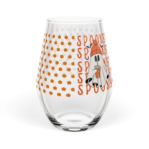 Puede incluir: Un vaso transparente sin tallo con un patrón repetitivo de pequeñas calabazas naranjas en el lado izquierdo. El lado derecho muestra la palabra SPOOKY repetida verticalmente en naranja, junto a un fantasma con gorro naranja y una bebida.