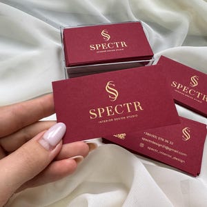 May include: Red business cards with gold lettering. The cards feature the logo "S" and the text "SPECTR INTERIOR DESIGN STUDIO". Contact information is included on the bottom of the card.