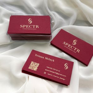 May include: A stack of burgundy business cards with gold lettering. The cards feature the logo "SPECTR Interior Design Studio" and contact information for Tetiana Melnyk.